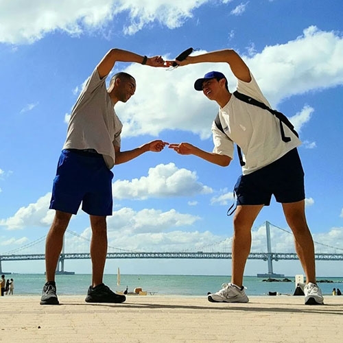 Two men making a square with their arms against an ocean scene