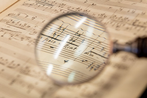 A musical manuscript of Franz Liszt with a magnifying glass in the foreground