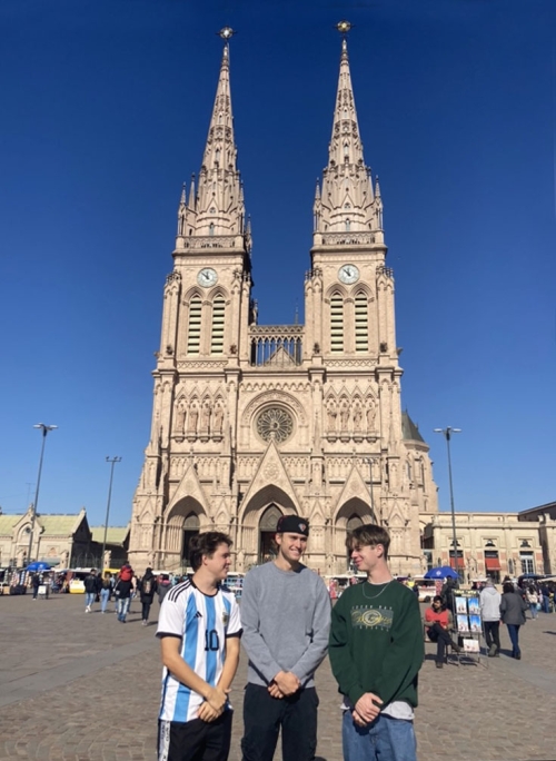 A two-towered stone building in Buenos Aires and three friends posing in front of it