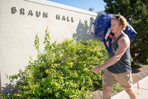 an Occidental College student heading in to Braun Hall with his duffel bag